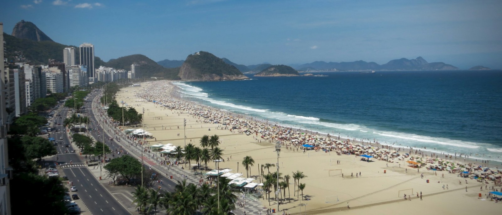 La playa de Copacabana en un día soleado, con la avenida Atlântica, sombrillas y el mar azul al fondo