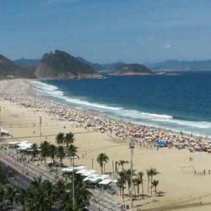 La playa de Copacabana en un día soleado, con la avenida Atlântica, sombrillas y el mar azul al fondo