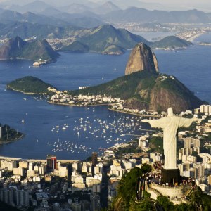 Vista aérea del Cristo Redentor sobre Río de Janeiro, con el Pão de Açúcar y la bahía de Guanabara bajo un cielo azul