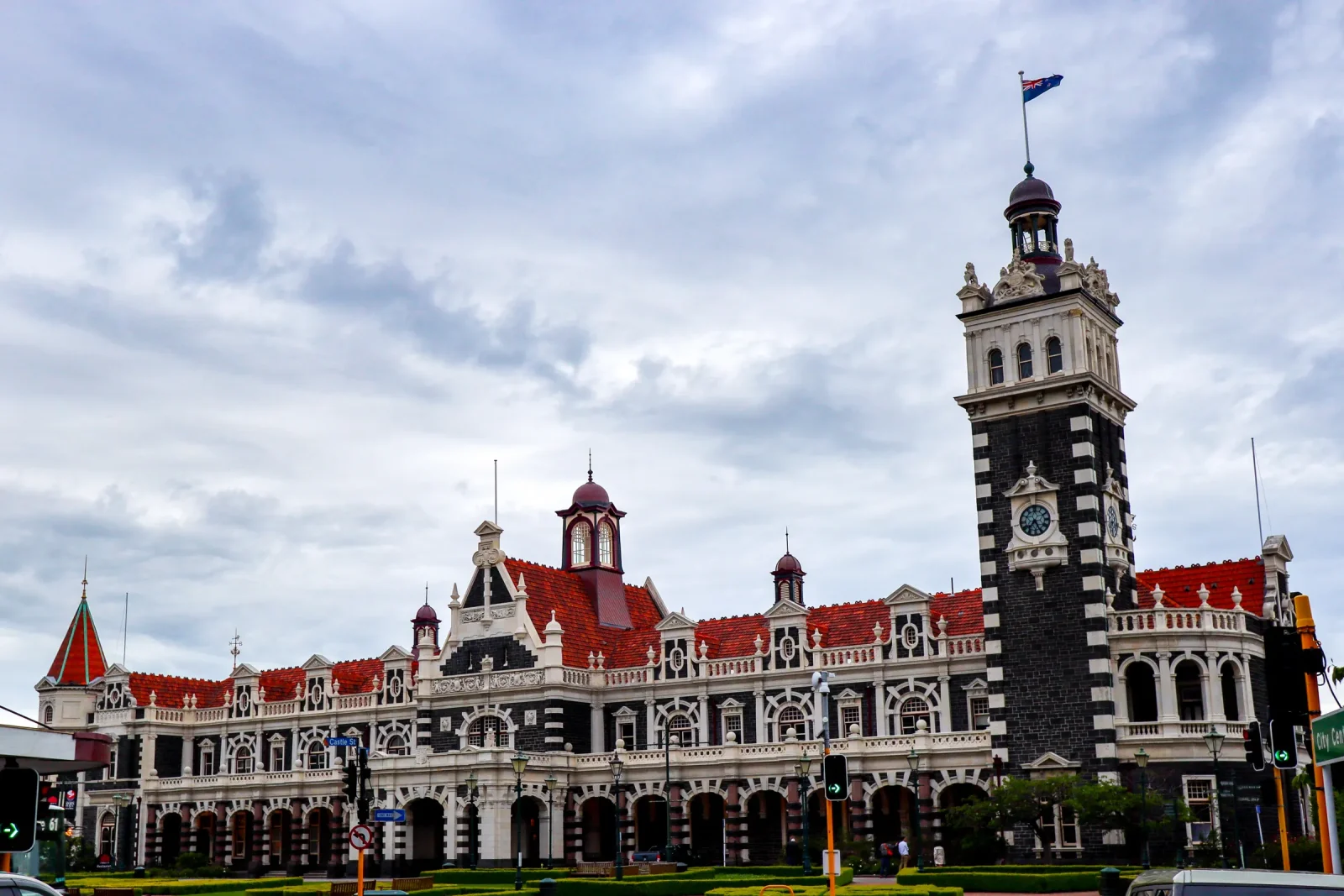Fachada de la estación de tren de Dunedin, de piedra clara y tejado rojo, con su torre del reloj