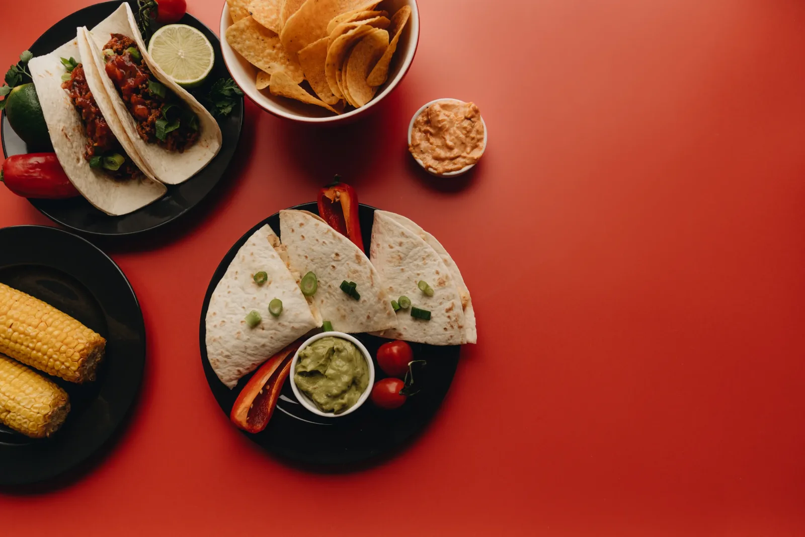 Una mesa con tacos, quesadillas, guacamole y salsas típicas de la cocina mexicana