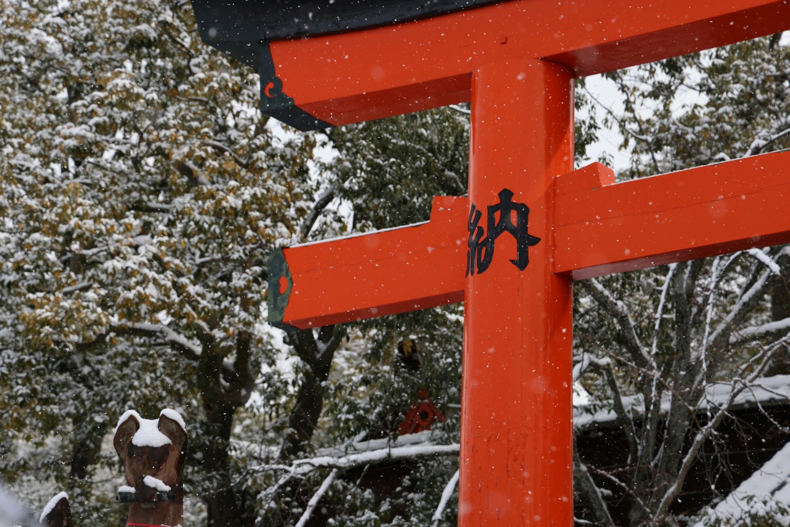 Puerta torii roja cubierta de nieve en un santuario japonés durante el invierno