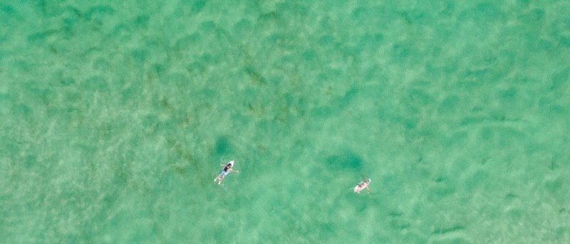 Vista aérea de surfistas en las aguas color esmeralda de Cabarita Beach, en el Tweed