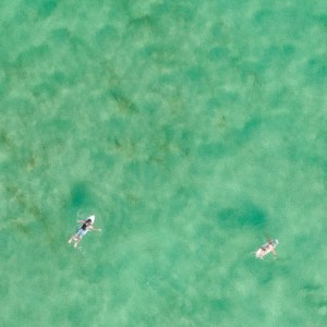 Vista aérea de surfistas en las aguas color esmeralda de Cabarita Beach, en el Tweed