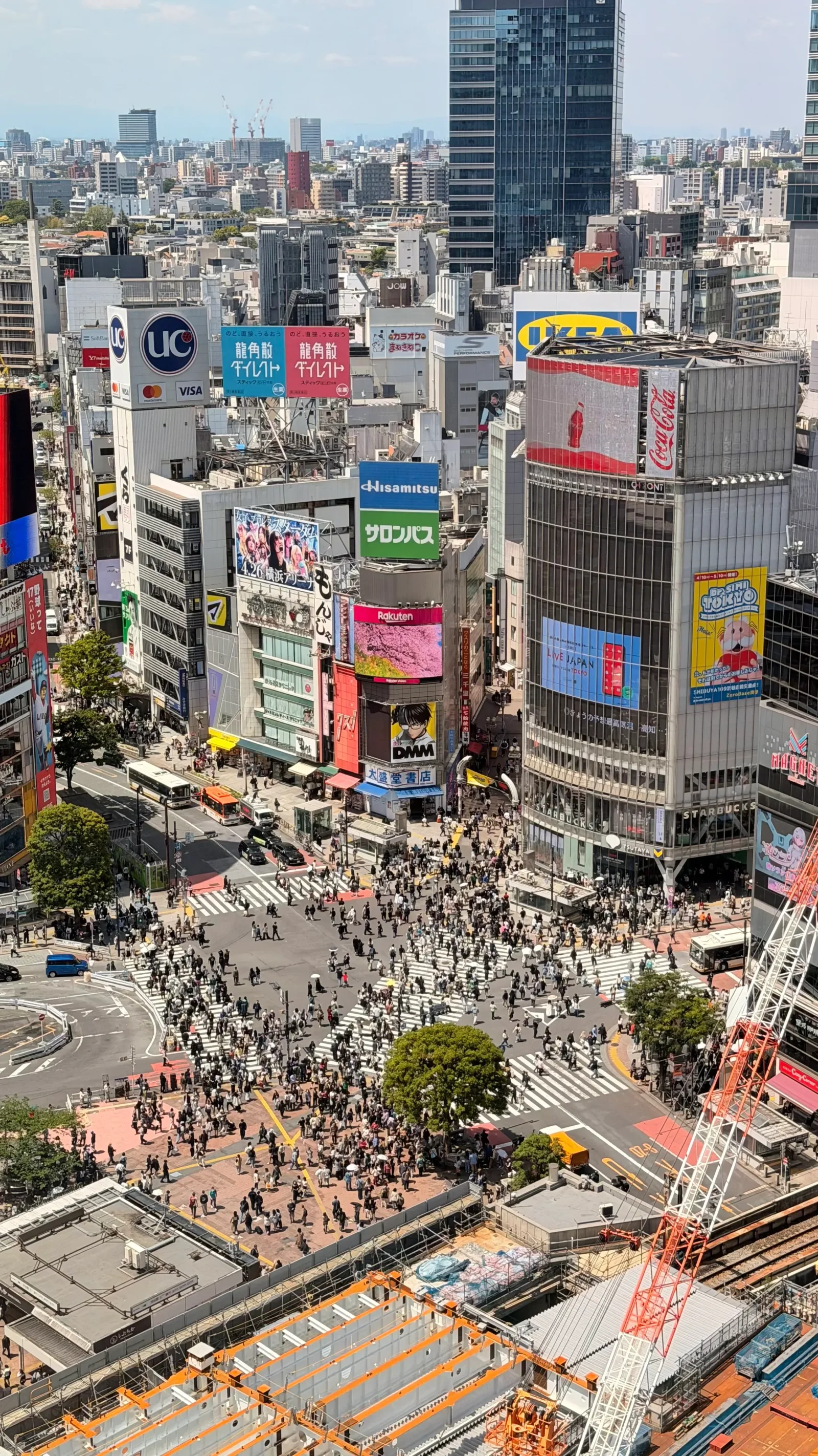 Vista aérea del cruce de Shibuya en Tokio, con peatones cruzando entre edificios y carteles