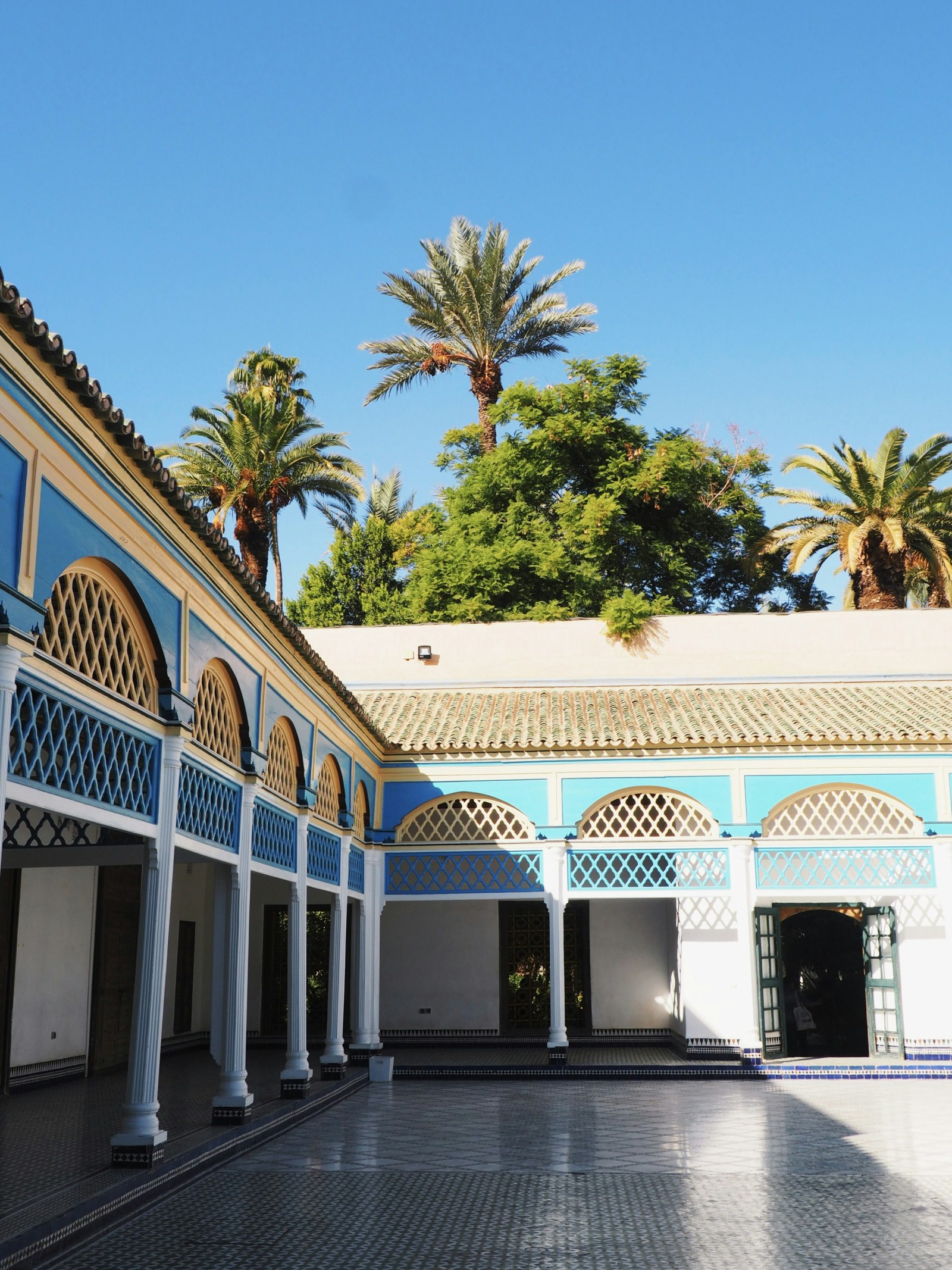 Patio de un riad marroquí con palmeras al fondo, en el Palacio de la Bahía de Marrakech.