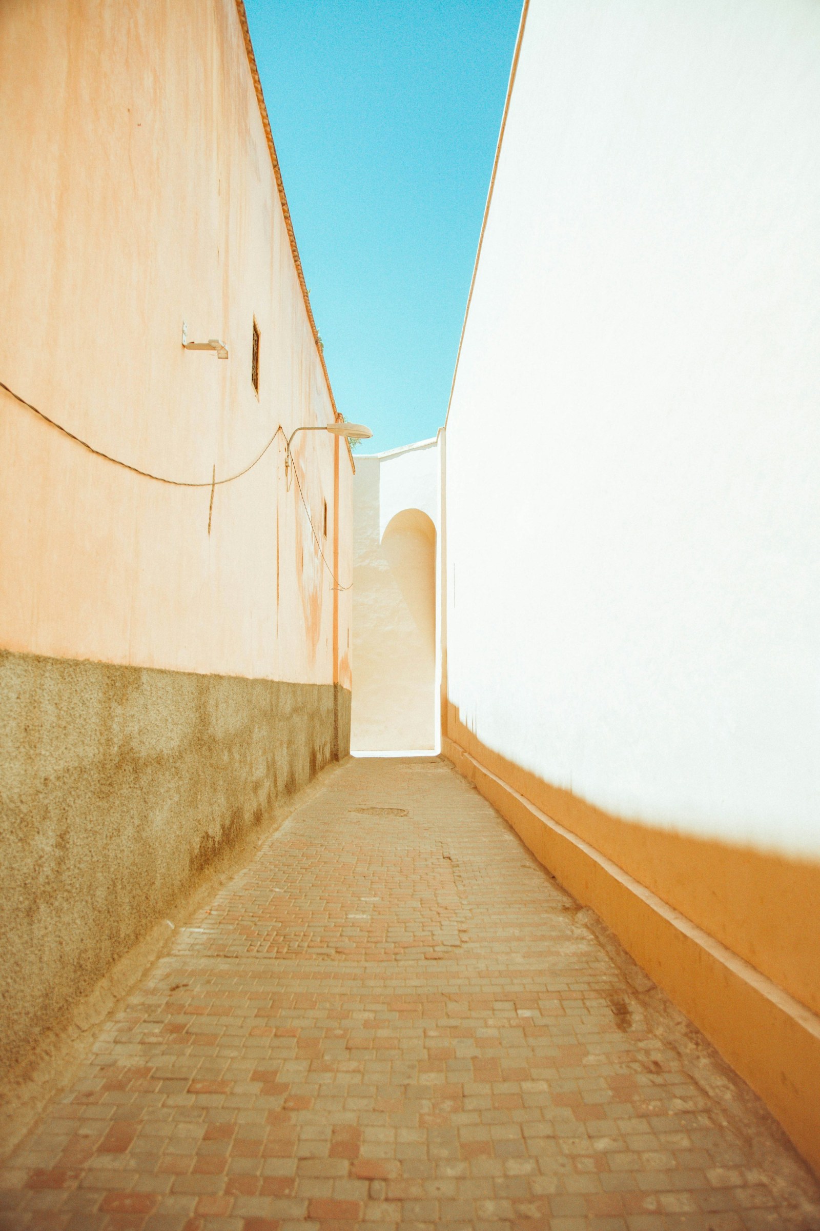 Callejón estrecho de la medina de Marrakech, con paredes blancas y un pasamanos de madera.