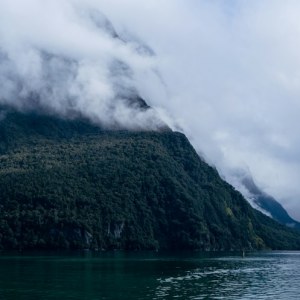 Mitre Peak reflejado en las aguas tranquilas del fiordo de Milford Sound, en la Isla Sur de Nueva Zelanda, con montañas entre la niebla