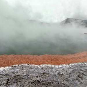 Aguas termales humeantes de colores turquesa y naranja en una zona geotérmica de Rotorua, Isla Norte de Nueva Zelanda