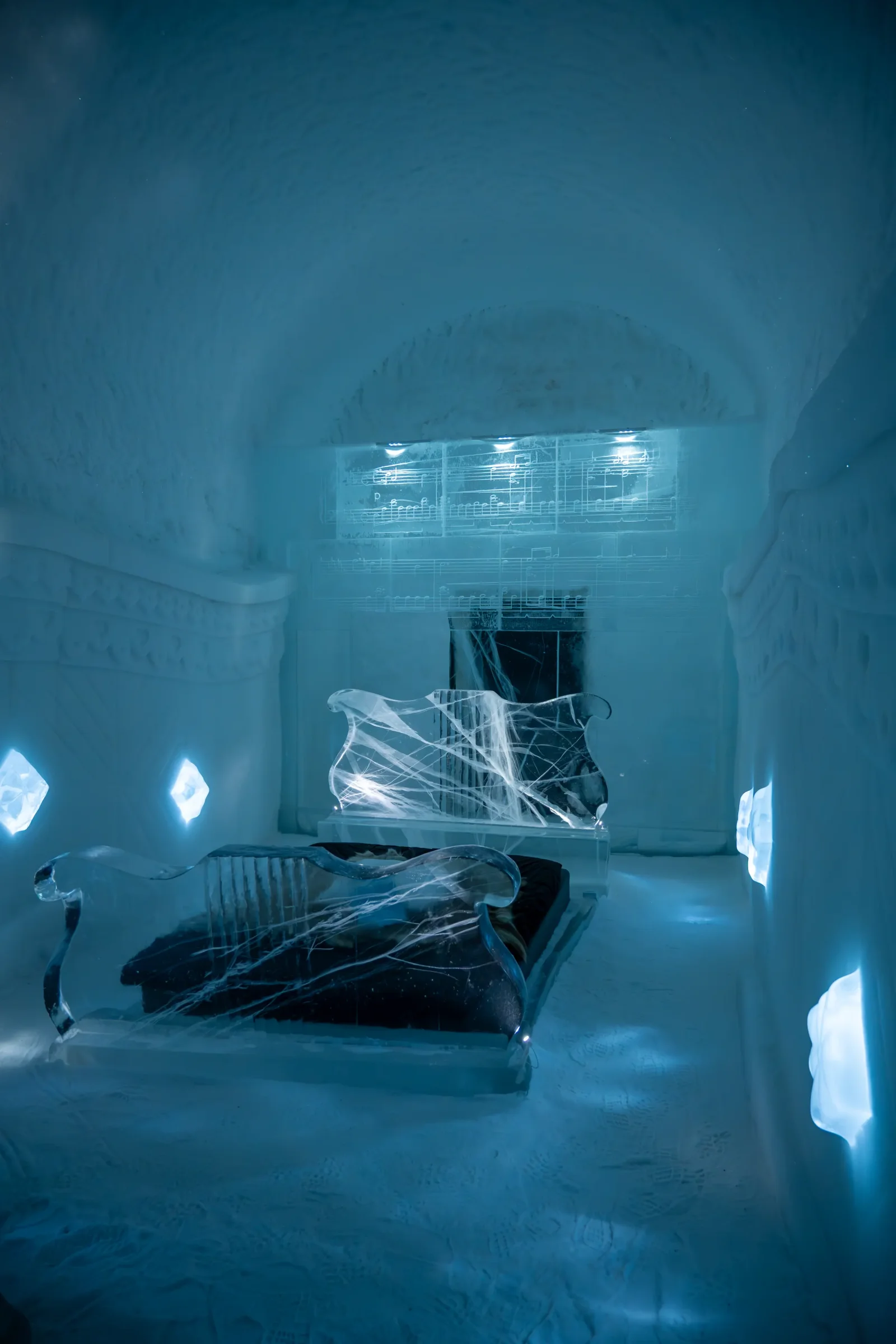 Habitación de hielo iluminada en azul, con esculturas talladas, en el hotel de hielo de Kiruna