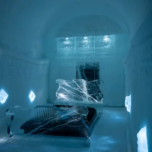 Habitación de hielo iluminada en azul, con esculturas talladas, en el hotel de hielo de Kiruna