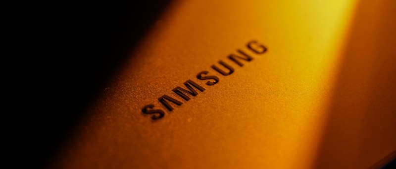 Logotipo de Samsung iluminado por un haz de luz dorada sobre fondo oscuro