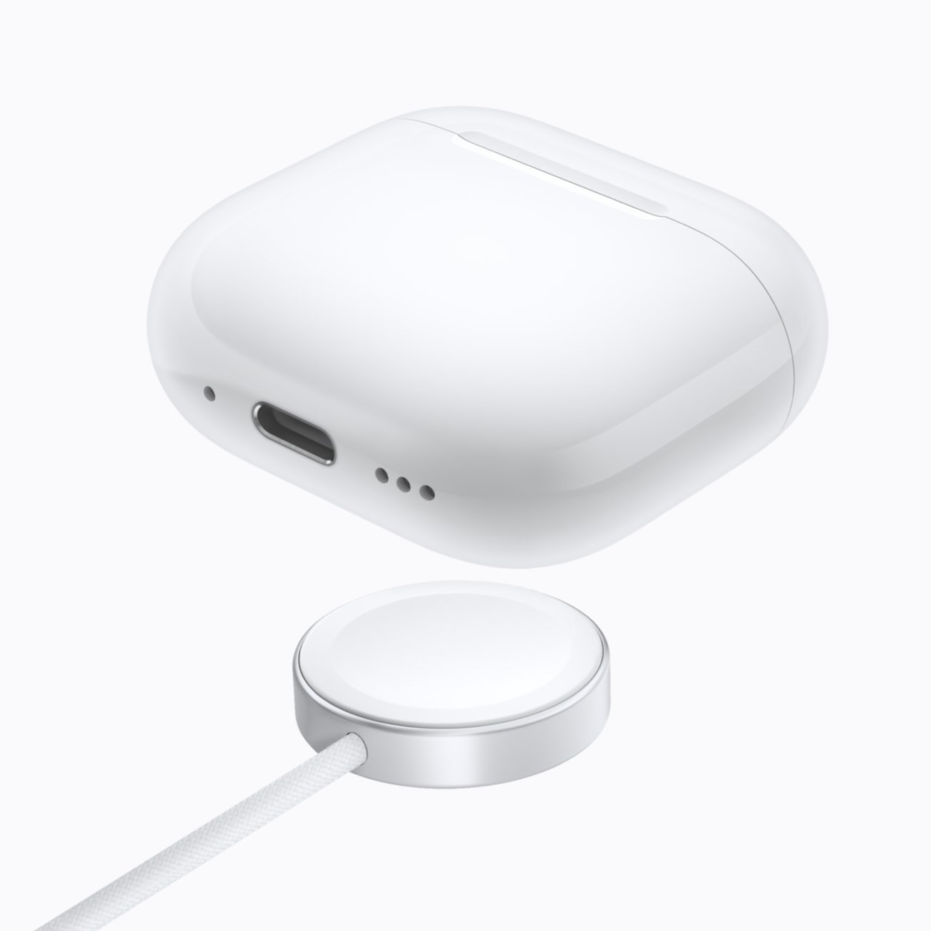 Estuche de carga inalámbrica de los AirPods 5 junto a su cargador, sobre fondo blanco