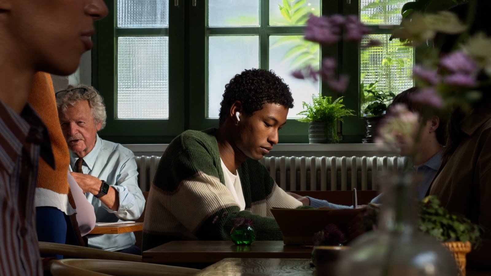 Una persona usa los AirPods 5 en una cafetería